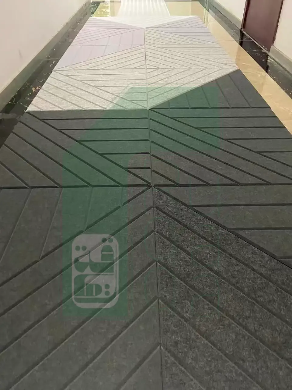 Ruqaqa acoustic felt panels in charcoal and white running along a corridor with a chevron-grooved geometric texture