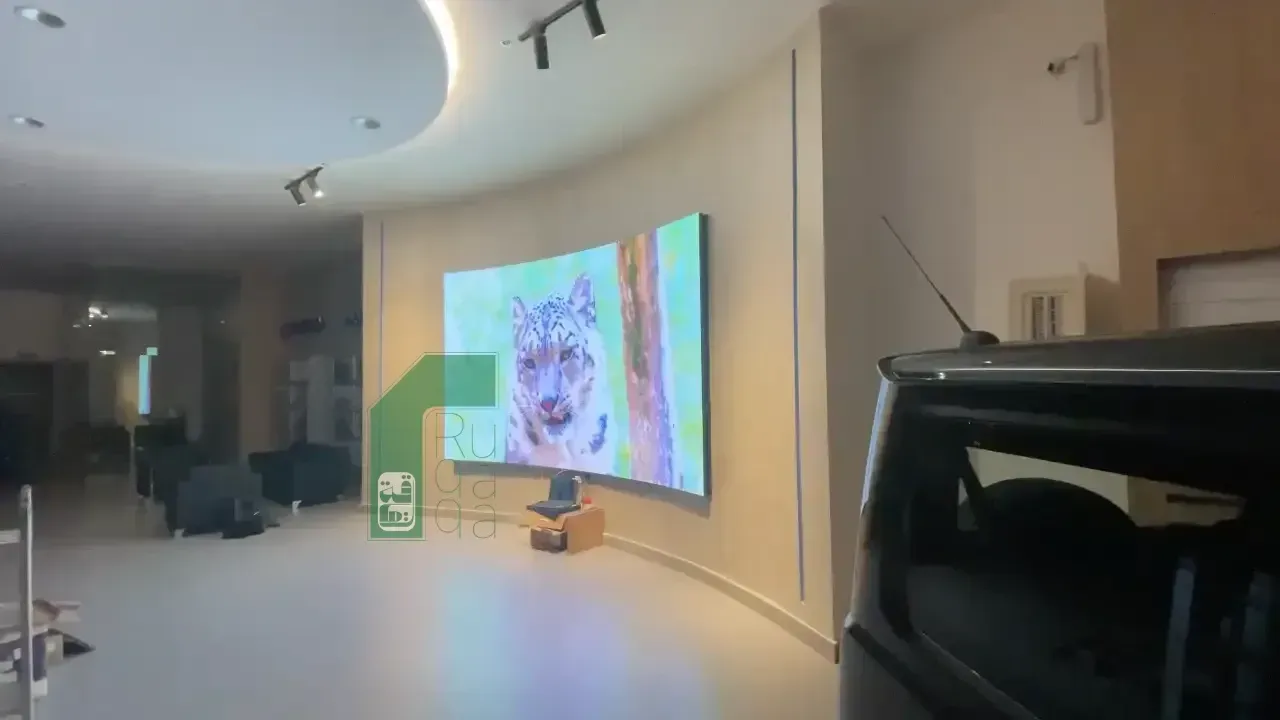 Ruqaqa curved LED screen wall-mounted in a showroom displaying high-definition content